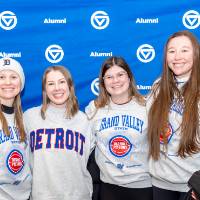 Group of four posing for photo in front of GV Alumni backdrop
